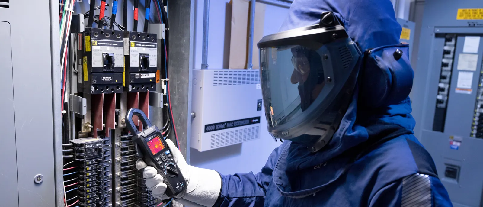 A thermal imaging clamp meter on a live panel, with the right protective equipment